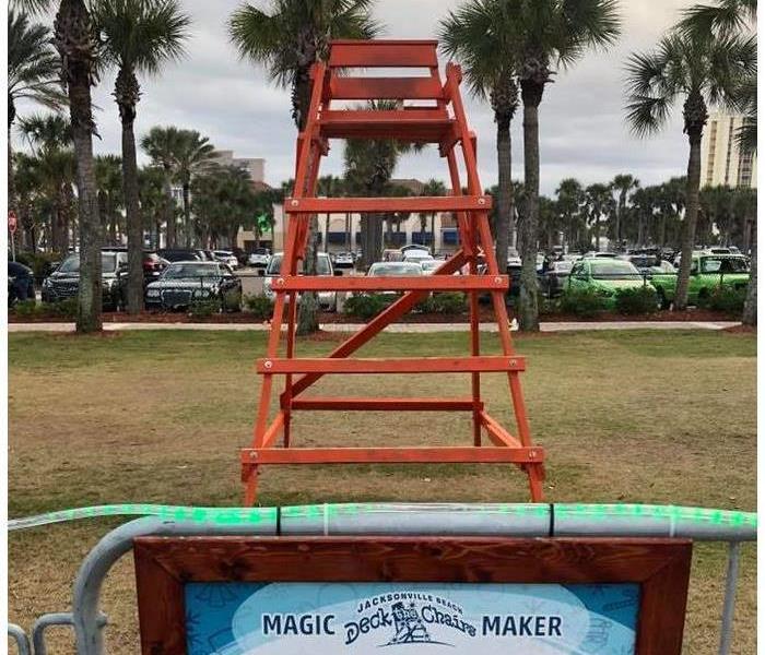 Image shows red lifeguard chair and green grass.