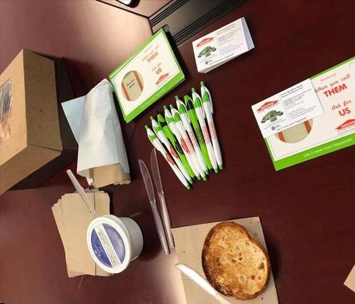Image shows a table with marketing material and bagels.