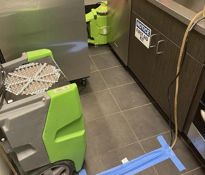 Images shows an office break room with green SERVPRO drying equipment.
