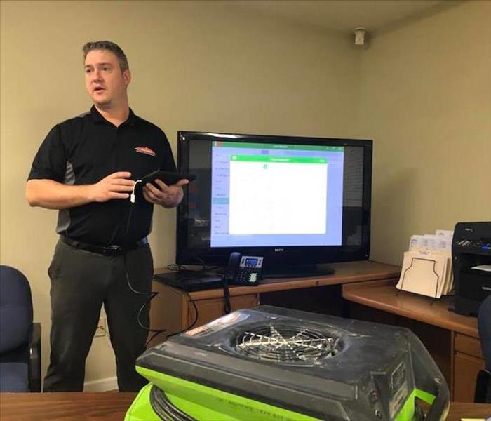 This photo shows our GM Benjamin leading a training session for our team. He is standing in front of a TV.