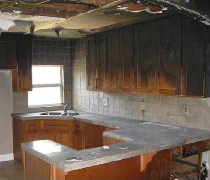 Image shows soot damage and black marks on brown kitchen cabinets after a fire.