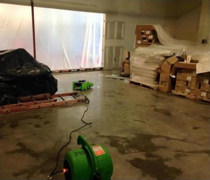 Photo shows a commercial property wish moisture on the concrete slab floor, with SERVPRO fans drying it out.