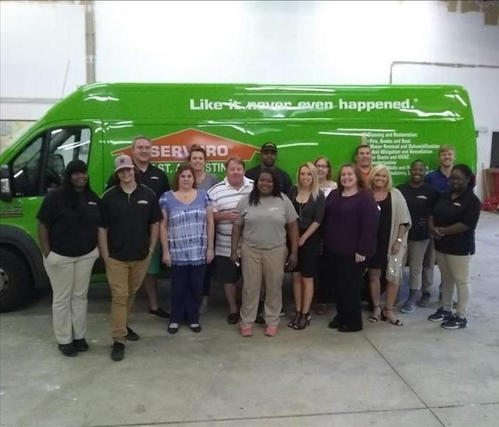 Photo shows SERVPRO of Jacksonville Beach/Ponte Vedra employees posing in front of a green truck in our warehouse.