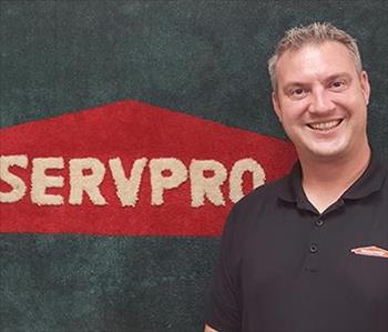 Image shows male SERVPRO Employee in front of sign.